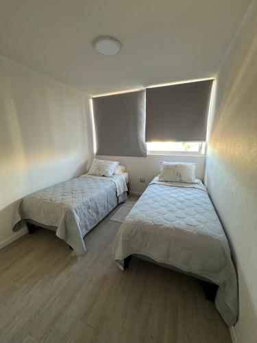 a room with two beds and a window at Moderno Departamento Viña del Mar in Viña del Mar