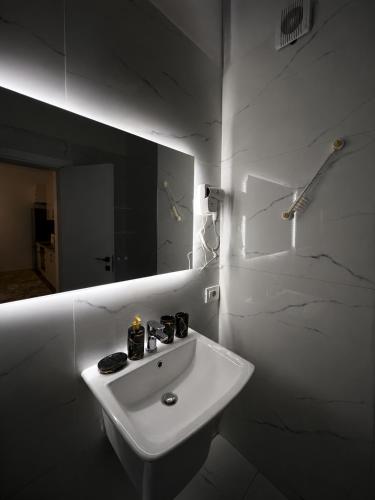 a white bathroom with a sink and a mirror at ARMAS Stay in Kamëz