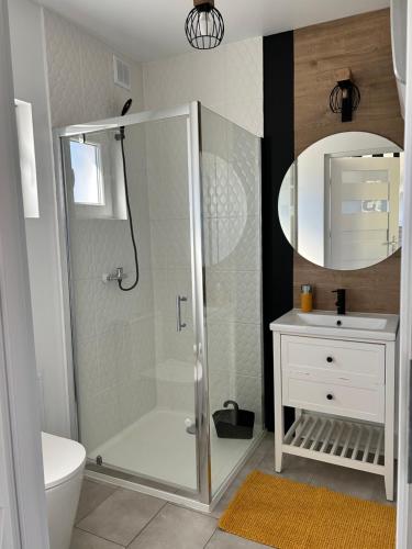 a bathroom with a shower and a sink and a mirror at Poprzeczna 7 in Sarbinowo