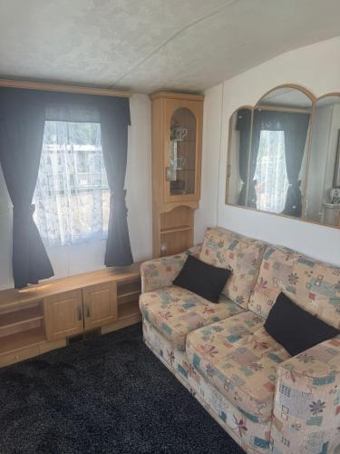 a living room with a couch and two windows at Kathy's Warden springs caravan in Leysdown-on-Sea