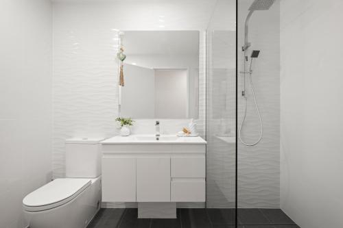 a white bathroom with a toilet and a sink at The Dunes Cotton Tree in Maroochydore