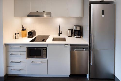 a kitchen with white cabinets and a stainless steel refrigerator at Revival English Bay, Vancouver in Vancouver