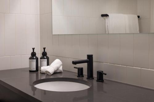 a bathroom sink with two bottles of wine and towels at Revival English Bay, Vancouver in Vancouver