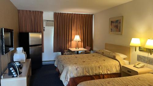 a hotel room with two beds and a television at DC Lodge in Dawson Creek