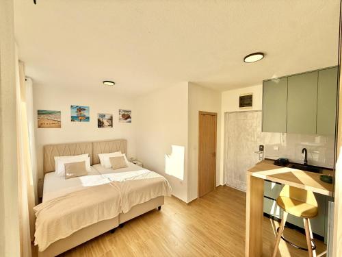 a bedroom with a bed and a desk and a kitchen at Modern Beachfront Apartment in Đenovići