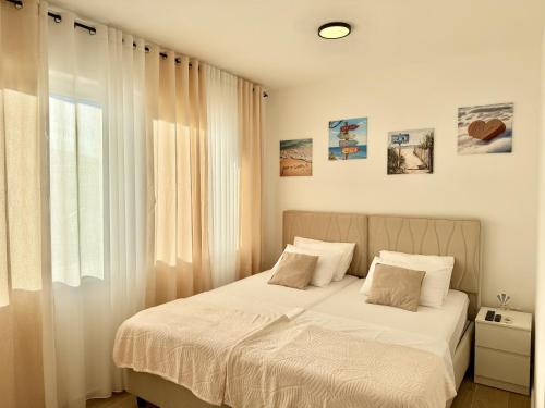 a bedroom with a bed with white sheets and a window at Modern Beachfront Apartment in Đenovići