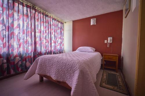 ein Schlafzimmer mit einem Bett und einem großen Fenster in der Unterkunft Hotel Los Alamos in Riobamba