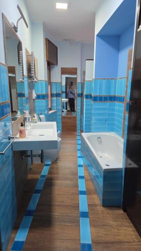 a bathroom with blue tiles and a tub and a sink at Holiday House Herculaneum in Ercolano