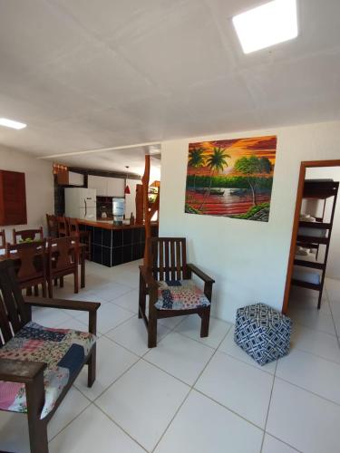 a living room with wooden chairs and a kitchen at Pousada pôr do sol in Cairu