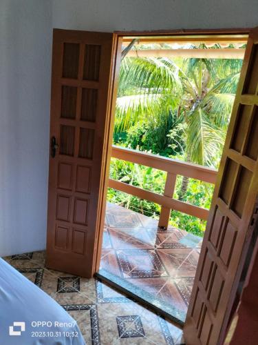 an open door with a view of a palm tree at Pousada pôr do sol in Cairu