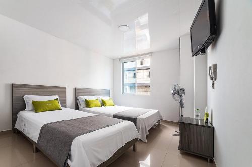 a bedroom with two beds and a flat screen tv at Hotel Exito La 21 in Pereira
