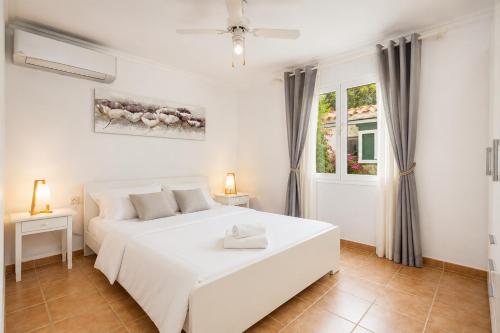 a white bedroom with a white bed and a window at Villa Maria Large Private Pool AC WiFi in Cala en Porter