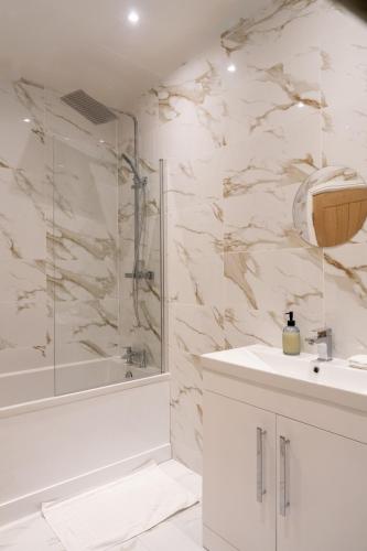 a white bathroom with a shower and a sink at 2 BR Apartment- Private Parking in Newport