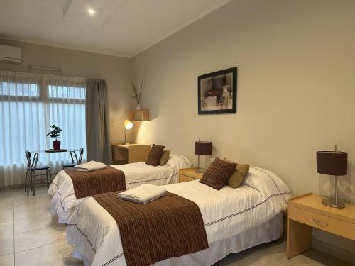a hotel room with two beds and a table at Los Plátanos cabañas & suites in Moreno
