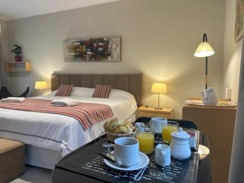 a hotel room with a bed and a table with a tray of food at Los Plátanos cabañas & suites in Moreno