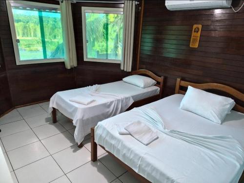 a room with two beds and two windows at Cabana do Parque in Presidente Figueiredo
