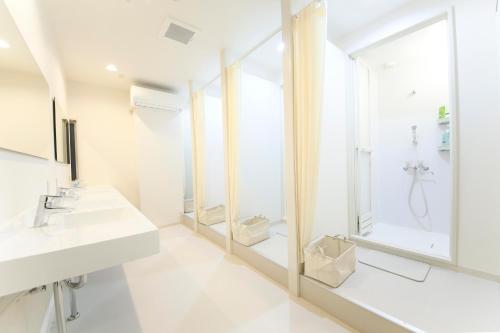 uma casa de banho branca com um lavatório e um espelho em Roots Hostel em Osaka