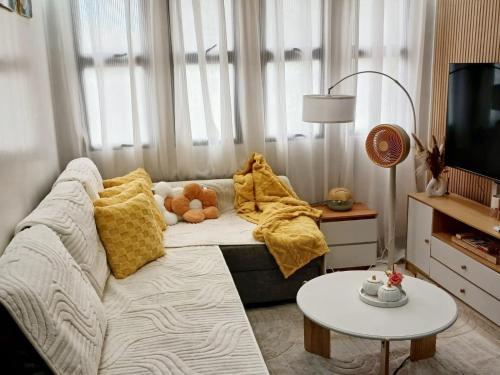 a living room with a white couch with yellow pillows at Y&S Residence in Olongapo