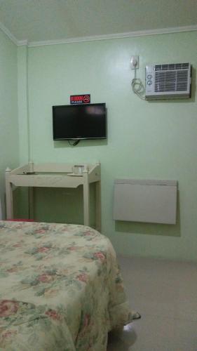 a bedroom with a bed and a tv on the wall at Dweller's Pensione in Iloilo City
