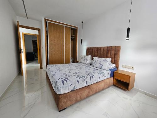 a bedroom with a large bed with a wooden headboard at Résidence EL AMAL in Martil