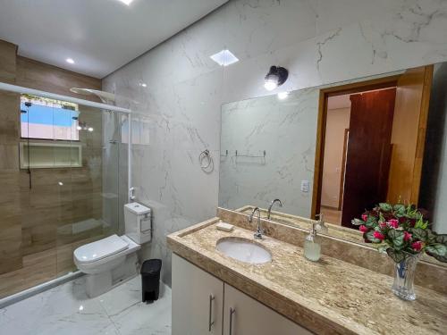 a bathroom with a sink and a toilet and a mirror at Casa Amoreira Paraty in Paraty