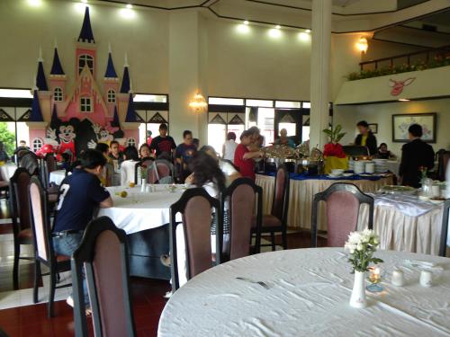 a group of people sitting at tables in a restaurant at Hotel Sibayak Internasional in Berastagi