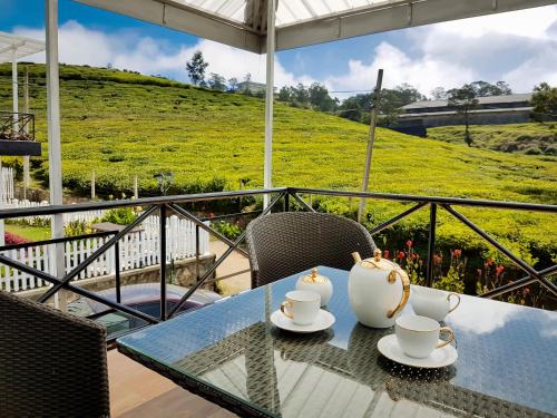 a table with two tea cups on top of a balcony at The Tea Garden in Nuwara Eliya