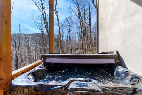 a hot tub in a window with a view of trees at Cozy Rustic Cabin in Sugar Mountain