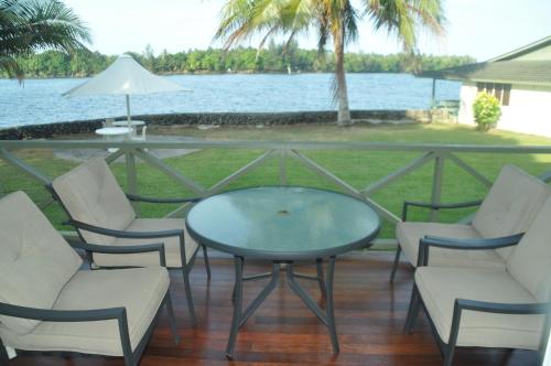 a glass table and chairs on a deck with the water at Madang Resort in Madang