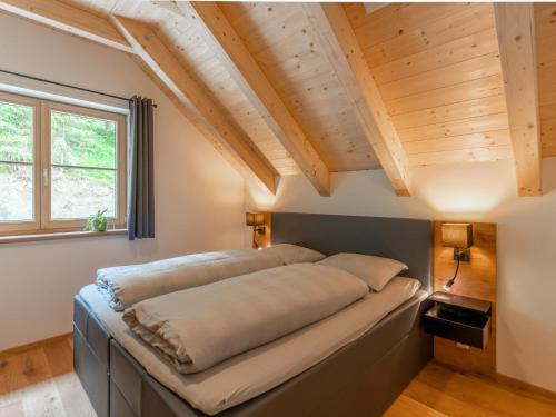 a bed in a room with wooden ceilings at Haus Ganbei in Donnersbachwald