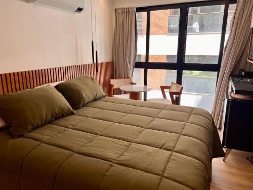a bedroom with a large bed and a large window at Cabo Branco Flat Amsterdam in João Pessoa