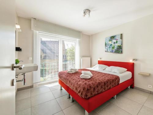 a bedroom with a red bed and a window at Elisa Beta in Nieuwpoort-Bad
