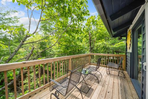 a deck with two chairs and a table on it at Treehouse On Beech in Beech Mountain