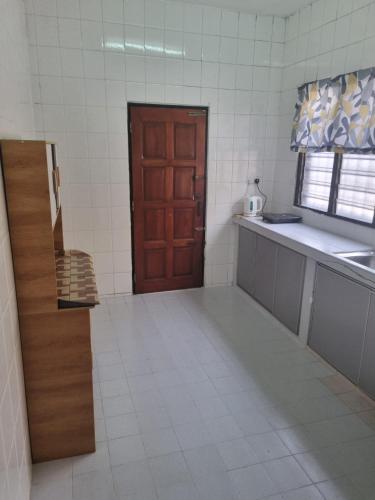 a kitchen with a brown door and a white tile floor at D' Saras Homestay in Sitiawan