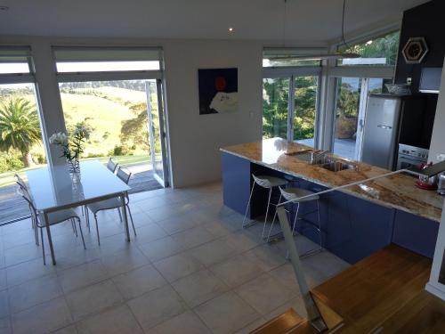 a kitchen with a counter and a table with chairs at Nikau Apartments Waiheke Island in Onetangi