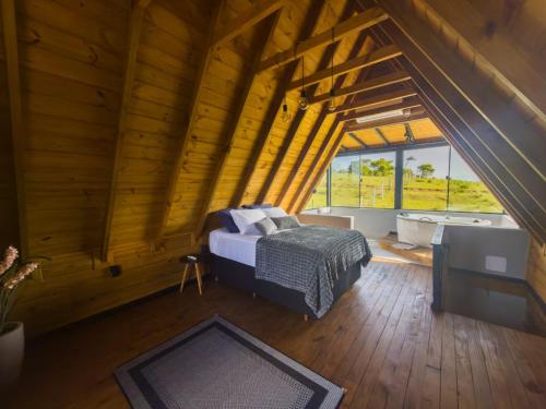 an attic bedroom with a bed and a bath tub at Chalé em laguna in Pescaria Brava