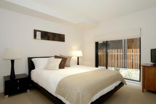 a white bedroom with a bed and a window at C-Scape water front apartment in Cowes