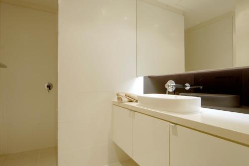 a white bathroom with a sink and a mirror at C-Scape water front apartment in Cowes