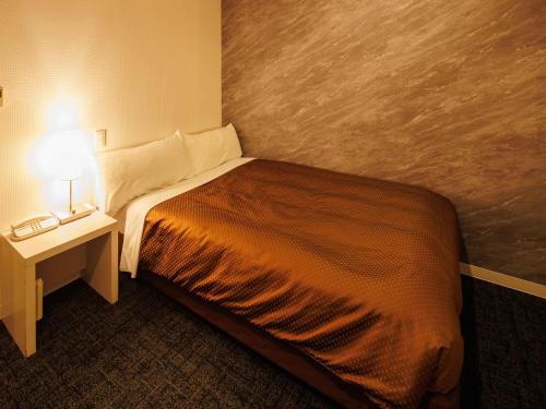 a bedroom with a bed and a night stand with a lamp at J Hotel Rinku in Tokoname