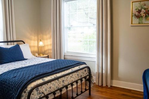 a bedroom with a bed with a blue blanket and a window at The Tea CottageStylishRain ShowerLocation in Starkville