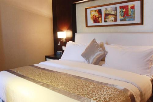 a bedroom with a bed with white sheets and pillows at National Park Hotel in Baljurashi