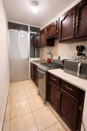 a kitchen with wooden cabinets and a stove top oven at Casa mezquite in Ocotlán
