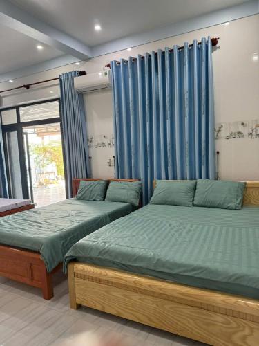 two beds in a room with blue curtains at KEN Homestay in Cu Lao Thu
