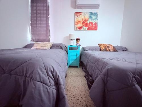 a bedroom with two beds and a blue table at Nice and Cozy House in the Greater Ponce Area in Ponce
