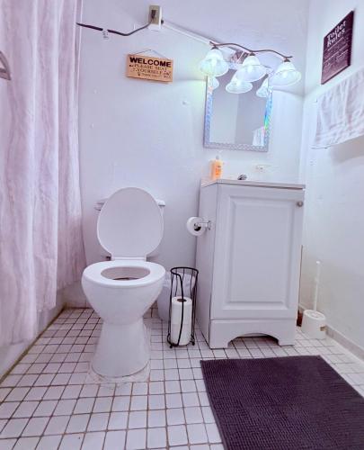 a white bathroom with a toilet and a mirror at Comfortable Apartment in the Greater Ponce Area in Ponce