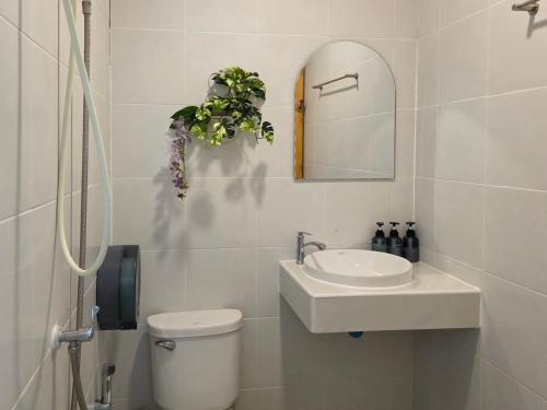a bathroom with a toilet and a sink and a mirror at ไวท์ เฮ้าท์ แคมป์ ชะอม in Ban Bung Mai