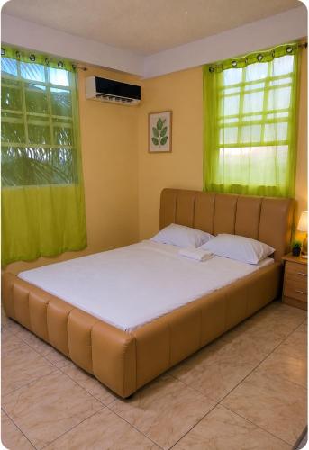 a large bed in a room with green curtains at Scenic 3 Bedroom Apartment And Car Rentals in Canefield