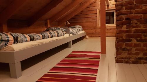 two beds in a attic room with a rug at Gamtunet Lyngen in Svensby