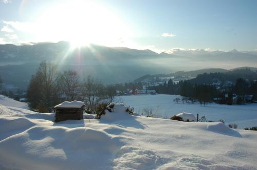 a snow covered hill with the sun in the background at Ferienwohnungen M Cichini in Millstatt