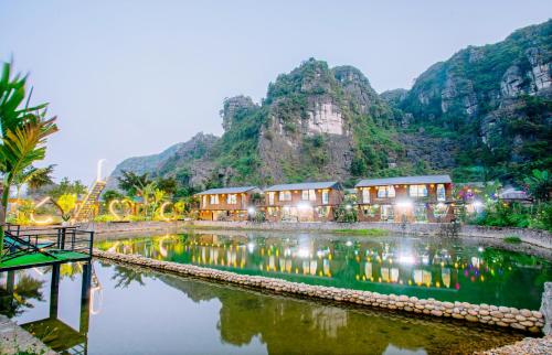 a resort with a lake in front of a mountain at Hang Mua Eco Park in Ninh Binh